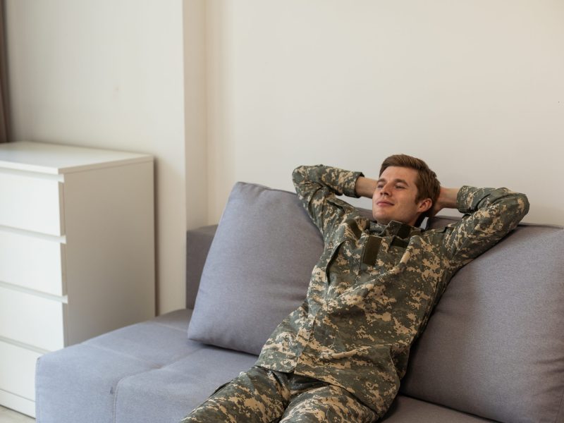 portrait of a positive man a professional military man in uniform sitting on a sofa with a living room at home